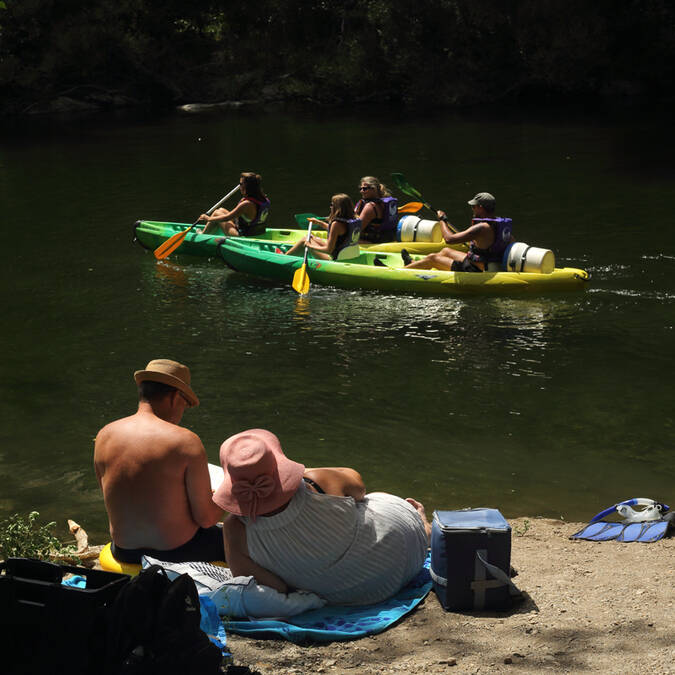 A family watches canoeists paddle by